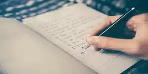 Hand die een pen vasthoudt en een checklist schrijft in een notitieboekje, Effectieve lijsten maken.