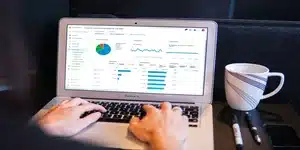 Een persoon die op een laptop werkt met grafieken en data-analyse op het scherm, het uitvoeren van een concurrentieanalyse wordt gesuggereerd door de focus op de statistieken en metrics die zichtbaar zijn.