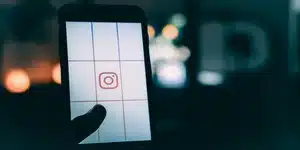 Een foto van een smartphone vastgehouden in een hand met een raster en het Instagram-logo gecentreerd, wat het proces van het maken van effectieve Instagram Stories impliceert met nadruk op compositie en planning.