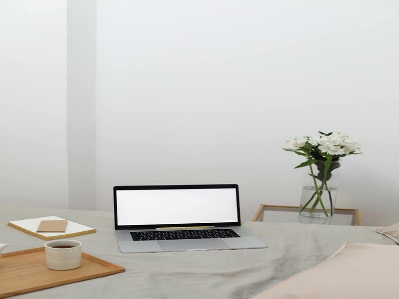 Een minimalistisch ingerichte werkplek met een laptop op tafel - een moderne interpretatie van het meervoud van 'copy'. De afbeelding nodigt uit tot nadenken over de transitie van fysieke naar digitale exemplaren in onze hedendaagse informatiemaatschappij.